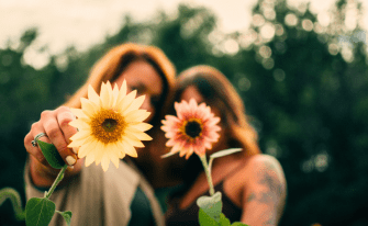 Frauen, die zusammen Blumen in die Kamera halten