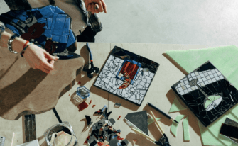 Mosaikbasteln mit Mosaiksteinen, Werkzeug und einer Person in der Ecke
