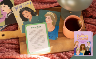 Ein gemütliches Arrangement auf einem Holztablett mit einer Tasse Tee und illustrierten Karten bekannter Persönlichkeiten wie Susan Sontag, Prinzessin Diana und Coco Chanel. Im Vordergrund liegt eine Infokarte zu Yoko Ono neben der lilafarbenen Box „Das Frauen Orakel“.