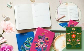 erminkalender 2027 aufgeschlagen, umgeben von drei kleinen Notizbüchern mit aufwendigen Blumen- und Vogelstickereien.