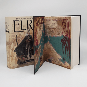 Elric Band hochstehend, so aufeklappt, dass die farbige Karte sichtabar ist, links daneben der Schutzumschlag mit Cover