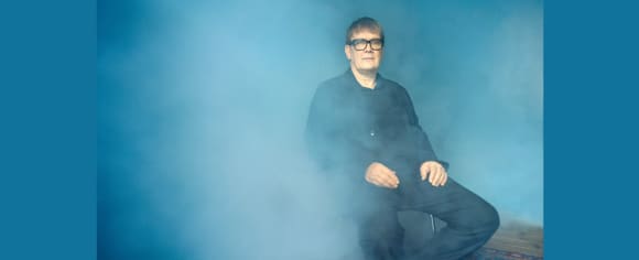 Sven Regener auf einem Stuhl sitzend, während Nebel aufsteigt