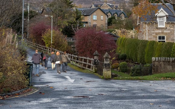 Ein schottisches Dorf mit ein paar Menschen von hinten, die auf der Straße gehen