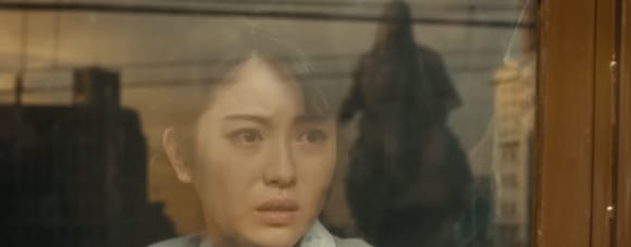 Godzilla Minus One: Frau blickt aus Fenster, in der Scheibe spiegelt sich Godzilla