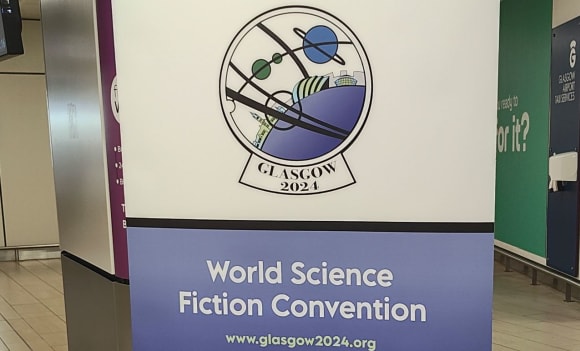 Ein Aufsteller vom Glasgower Flughafen, der auf den WorldCon 2024 hinweist.