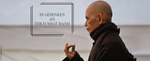 Thich Nhat Hanh sitz mit geschlossenen Augen meditierend in freier Umgebung. Daneben steht