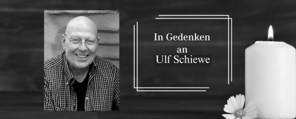 Ein schwarz weißes Porträt von Ulf Schiewe vor schwarzem Hintergrund und Kerze am rechten Bildrand