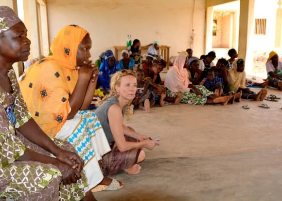 Katja Riemann und Bewohnerinnen des Frauenhauses in Burkina Faso sitzen zusammen und hören einem Vortrag zu