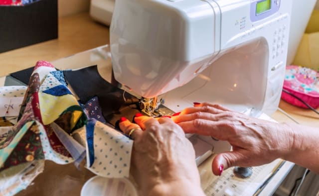 Frau an der Nähmaschine mit Stoffetzen