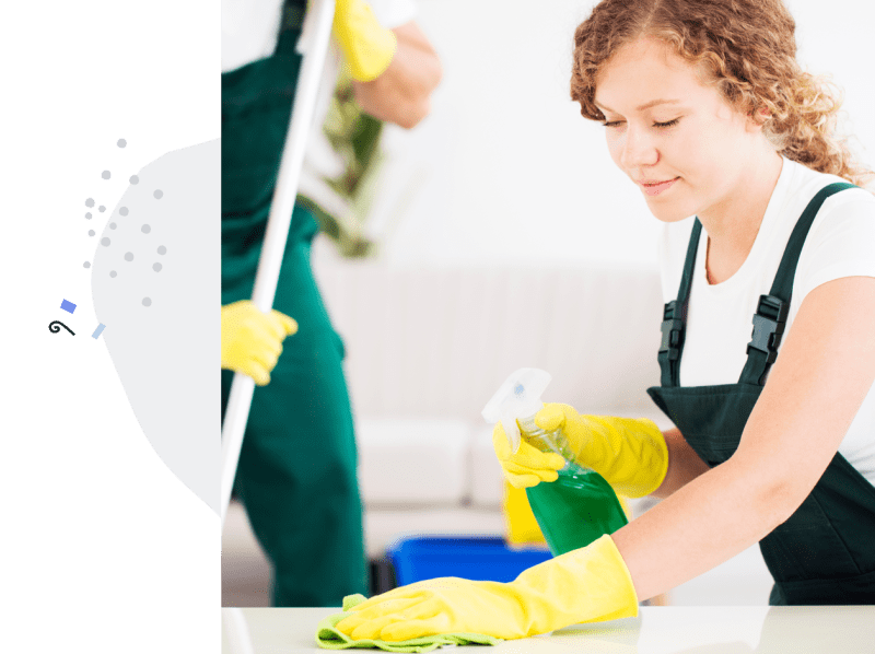 A woman in a cleaning business wipes a surface