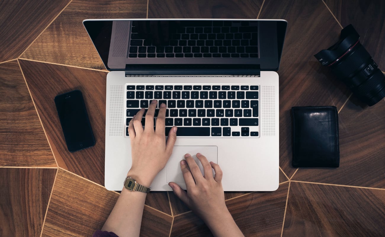 Overhead photo of a person typing on a laptop. Only their hands are shown