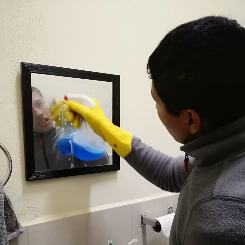 Diego cleaning a bathroom mirror