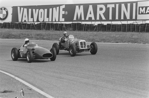 A black and white image of 2 F1 cars racing in 1950