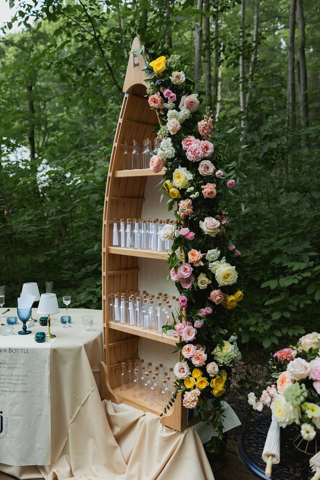 Wooden canoe shelf decorated with a lush floral cascade of pink, yellow, and cream roses at Sugar Lake Weddings