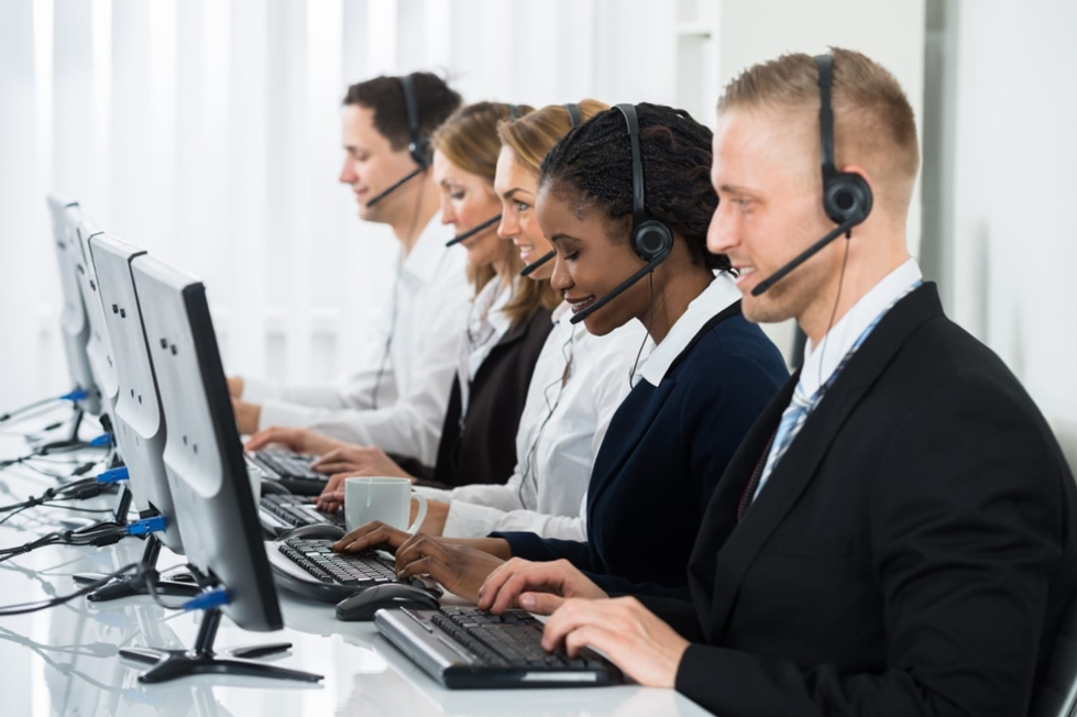 Five people using a call centre dialler on computers and headsets Five people using a call centre dialler on computers and headsets