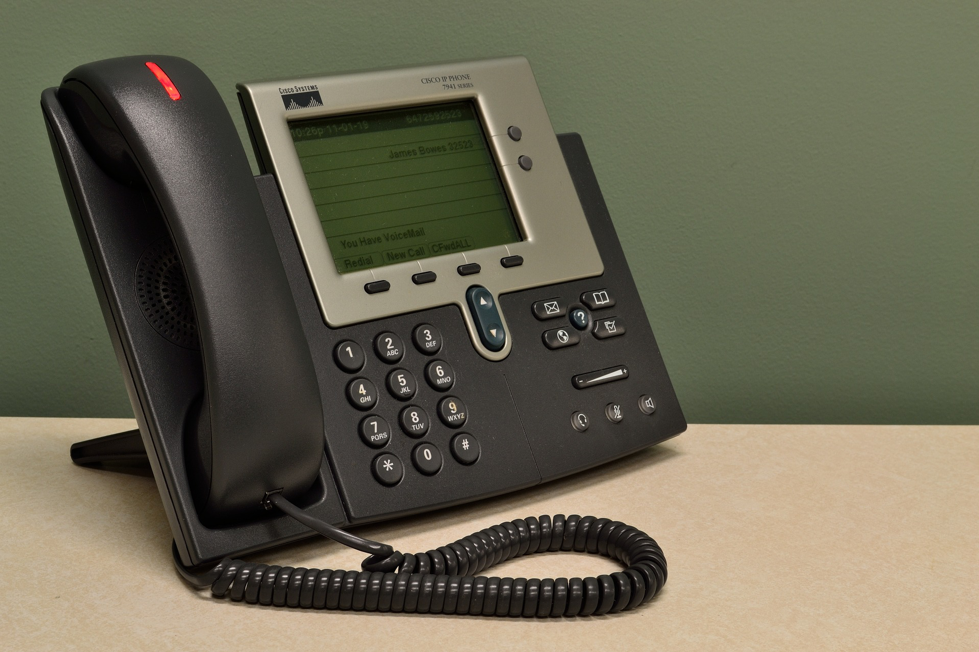 Black call centre dialler telephone on a brown table