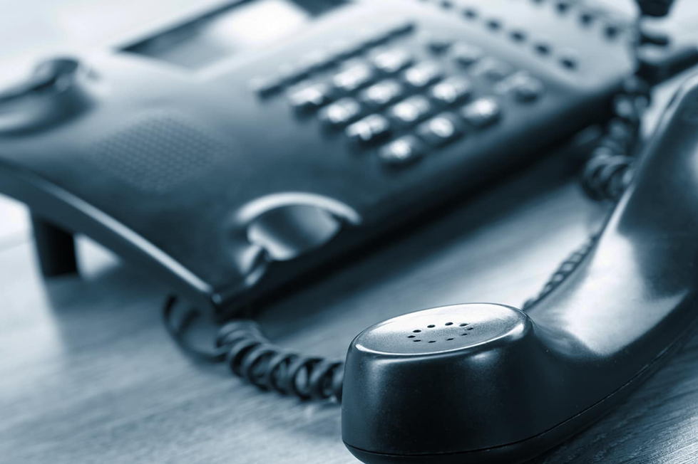 A black telephone with the receiver placed on a table A black telephone with the receiver placed on a table