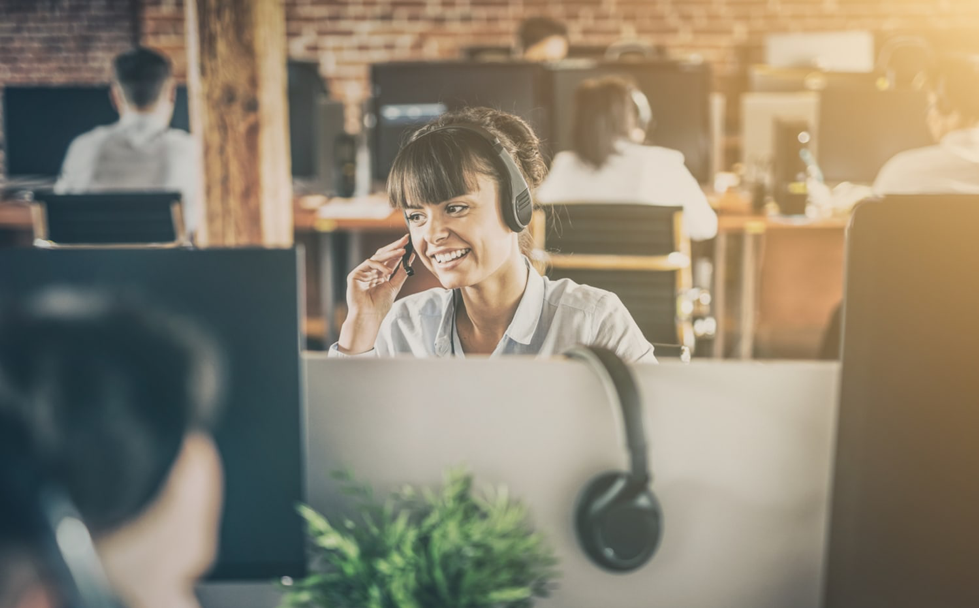 A woman smiling on a headset in a call centre A woman smiling on a headset in a call centre