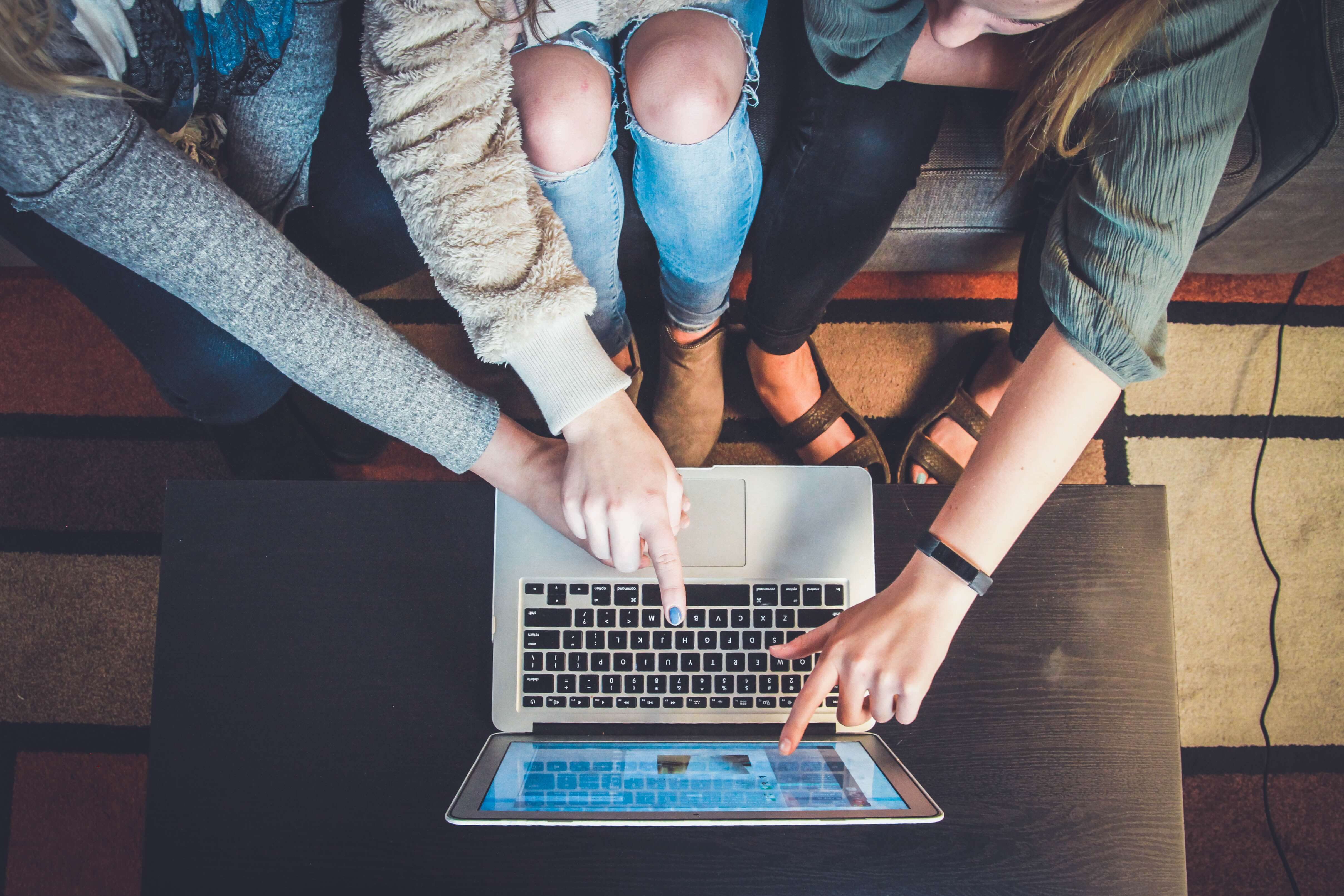 Three girls point at a laptop. Three girls point at a laptop.