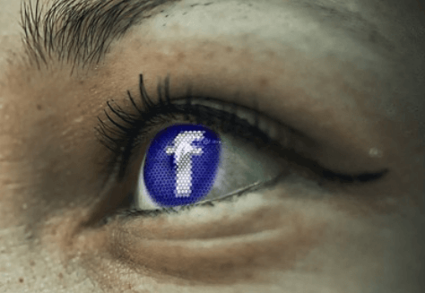An eye reflecting the Facebook logo. An eye reflecting the Facebook logo.