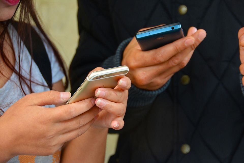 Two people texting on competing mobile phones Two people texting on competing mobile phones