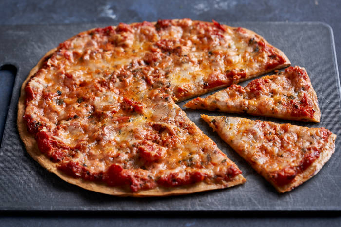 Quinoa pizza crust topped with tomato sauce and mozzarella