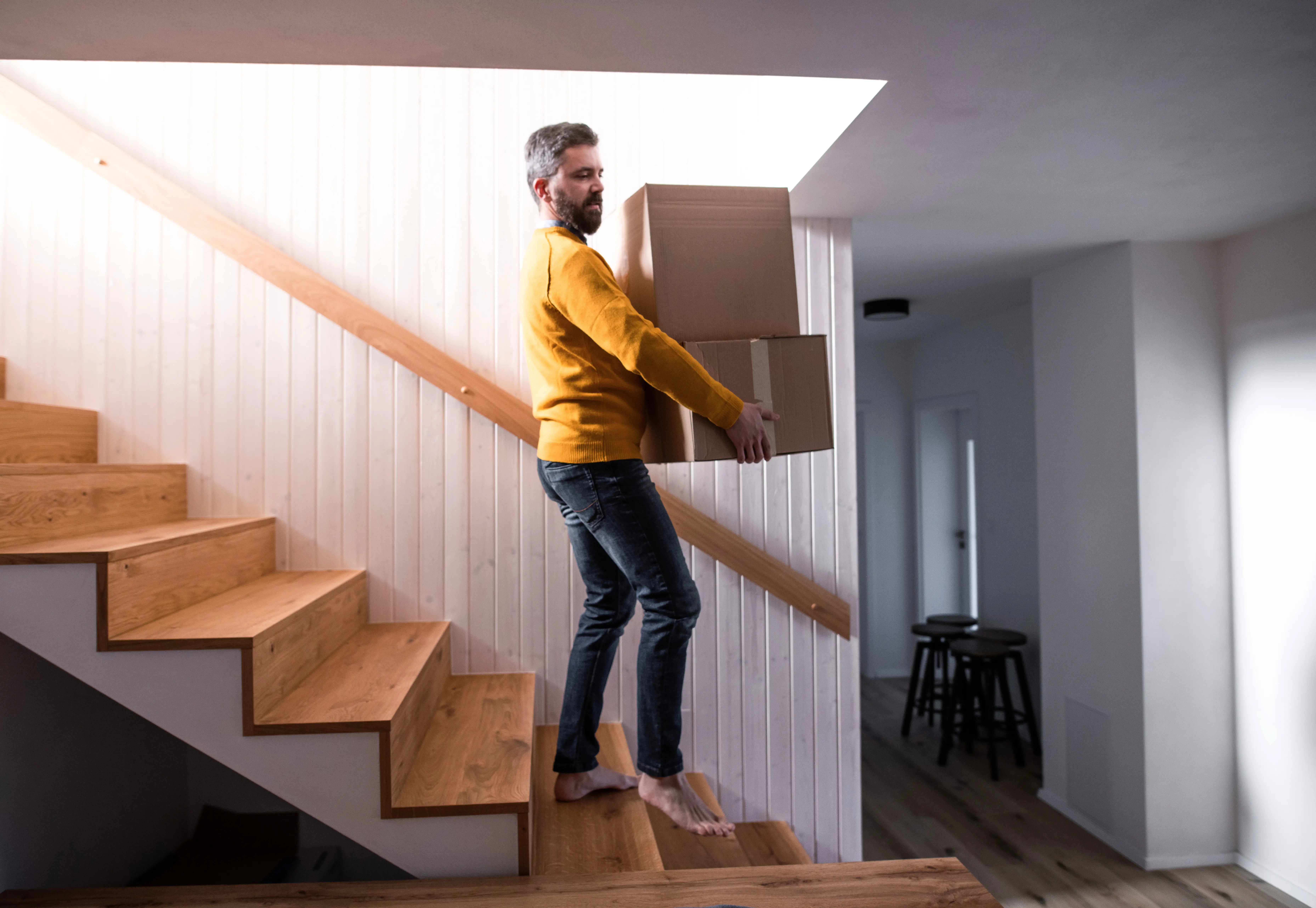 Man walking down stairs carrying moving boxes