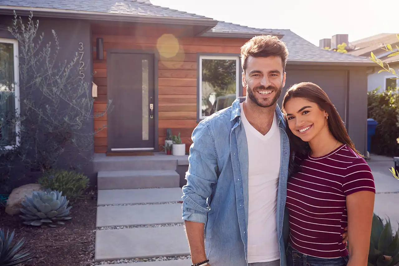 Smiling contemporary couple in front of house