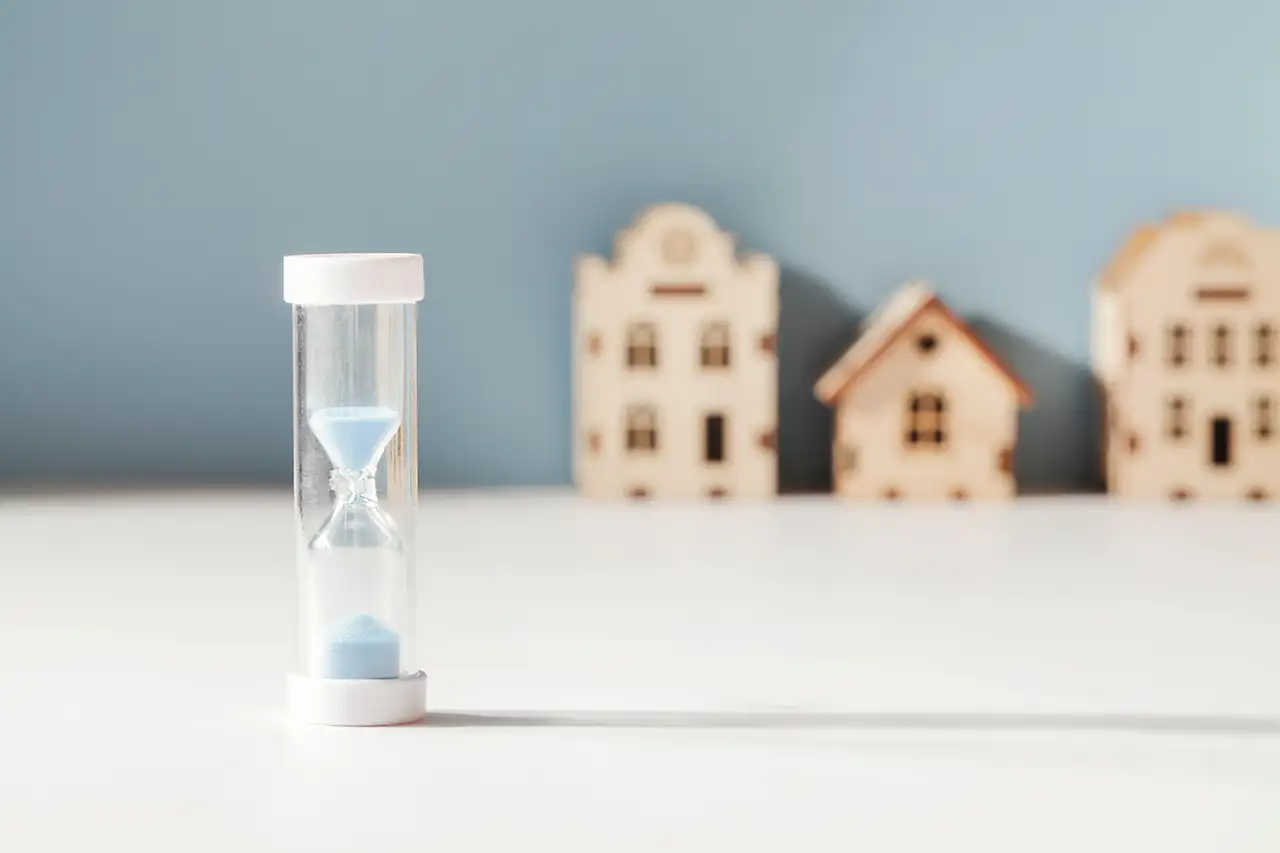 Concept image of real estate market with hourglass timer in foreground and toy houses in back