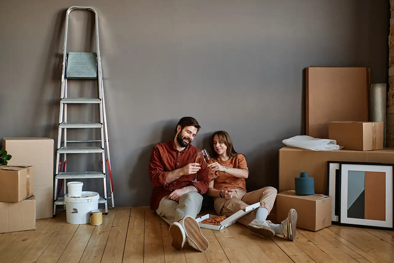 Couple celebrating home sale with champagne and pizza