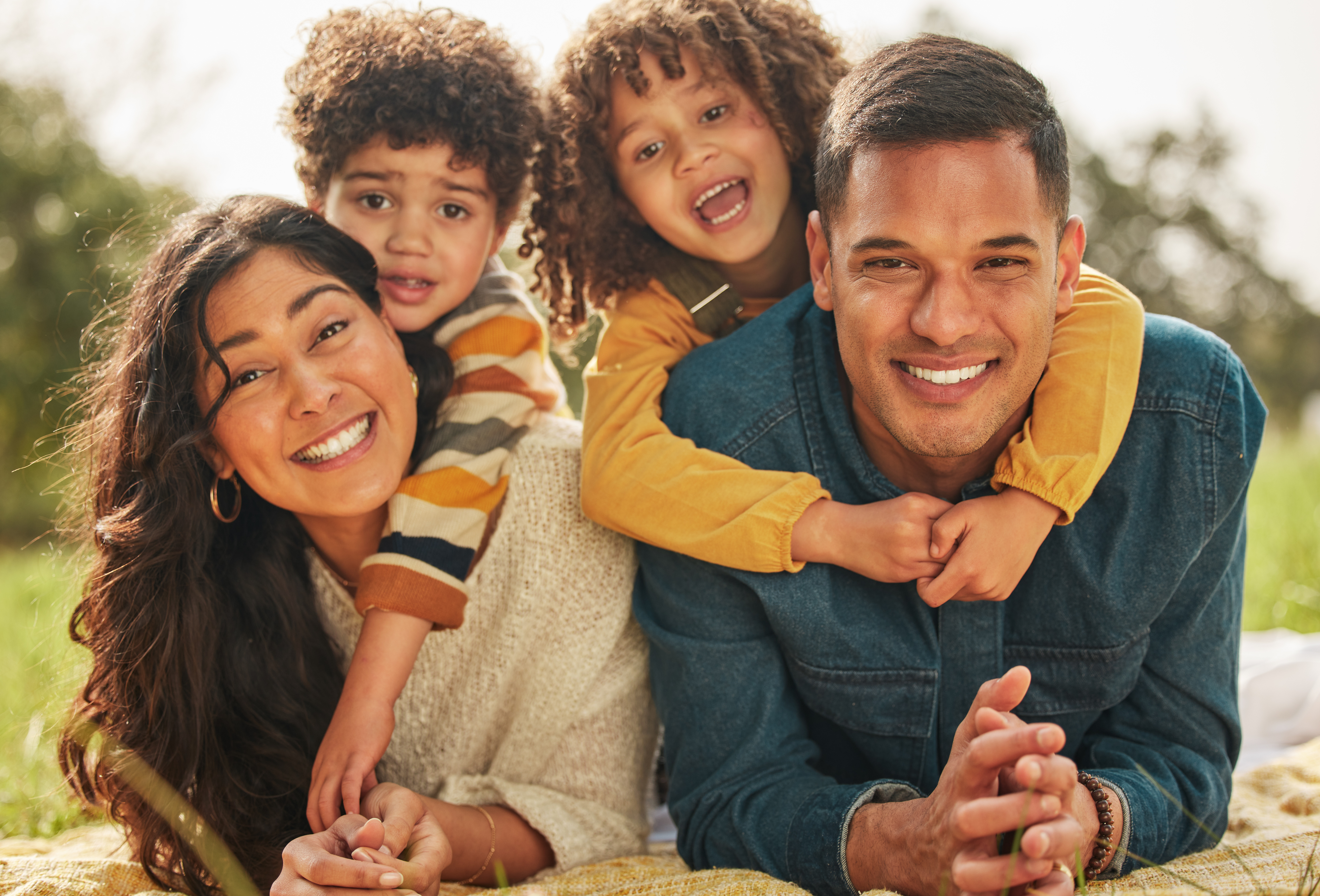 A happy couple with their children smiling together in a beautiful Bethesda, MD park