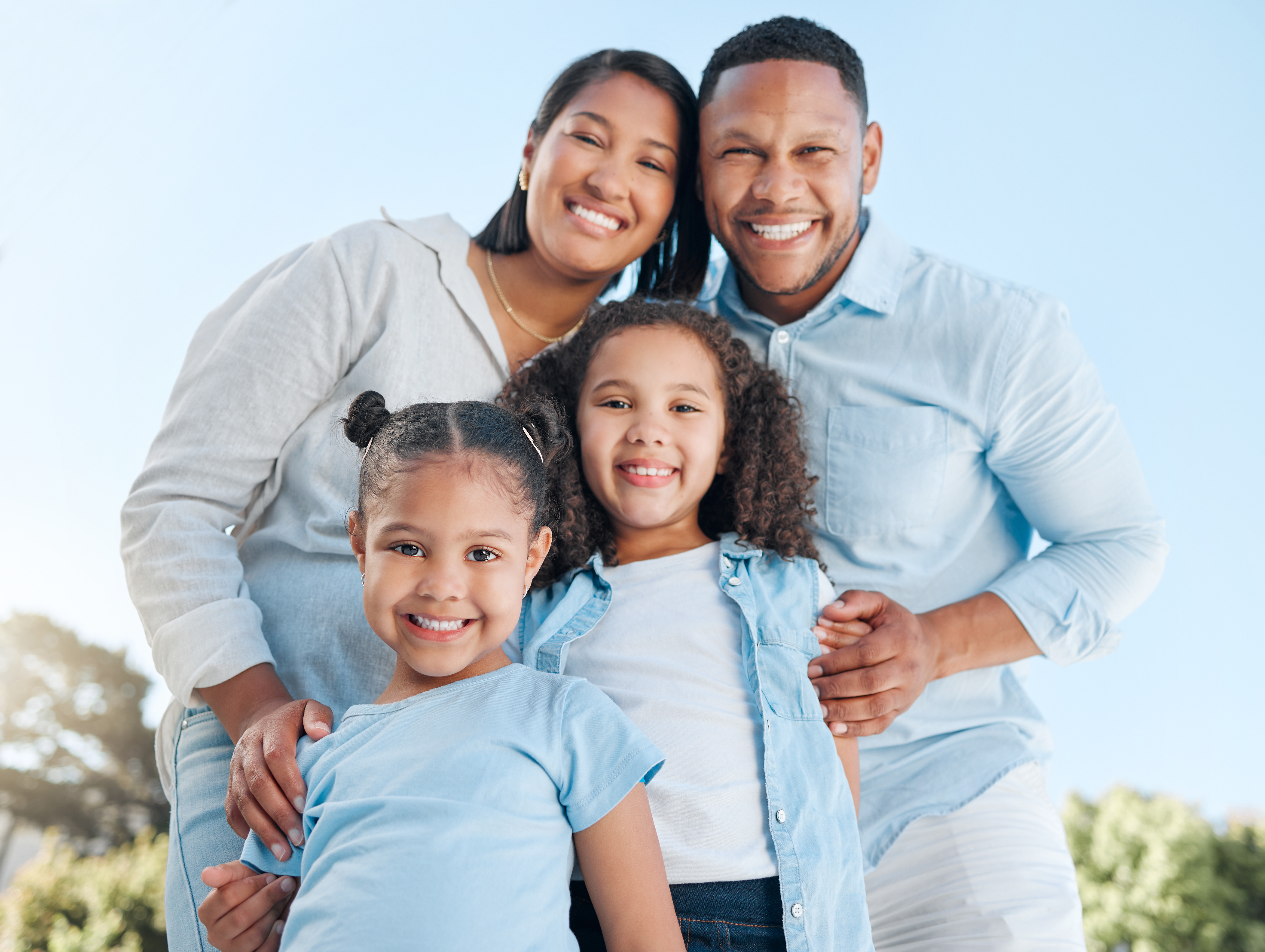 A happy family smiling together outdoors on a sunny day in Columbia, MD