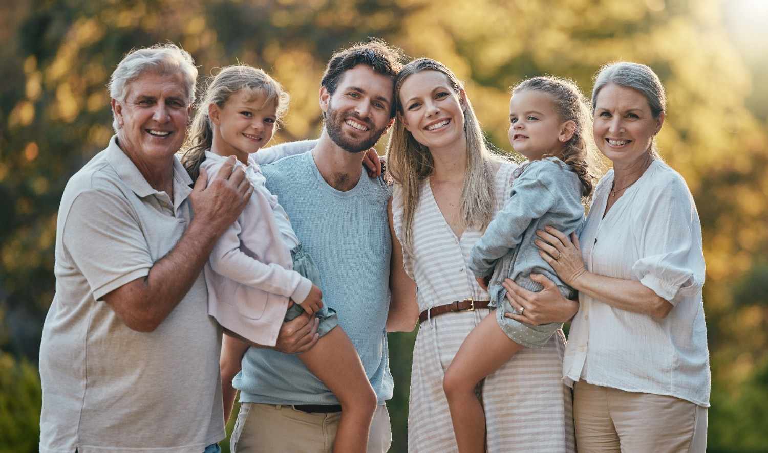 A happy, multi-generational family smiling together in a public park in Frederick, Maryland