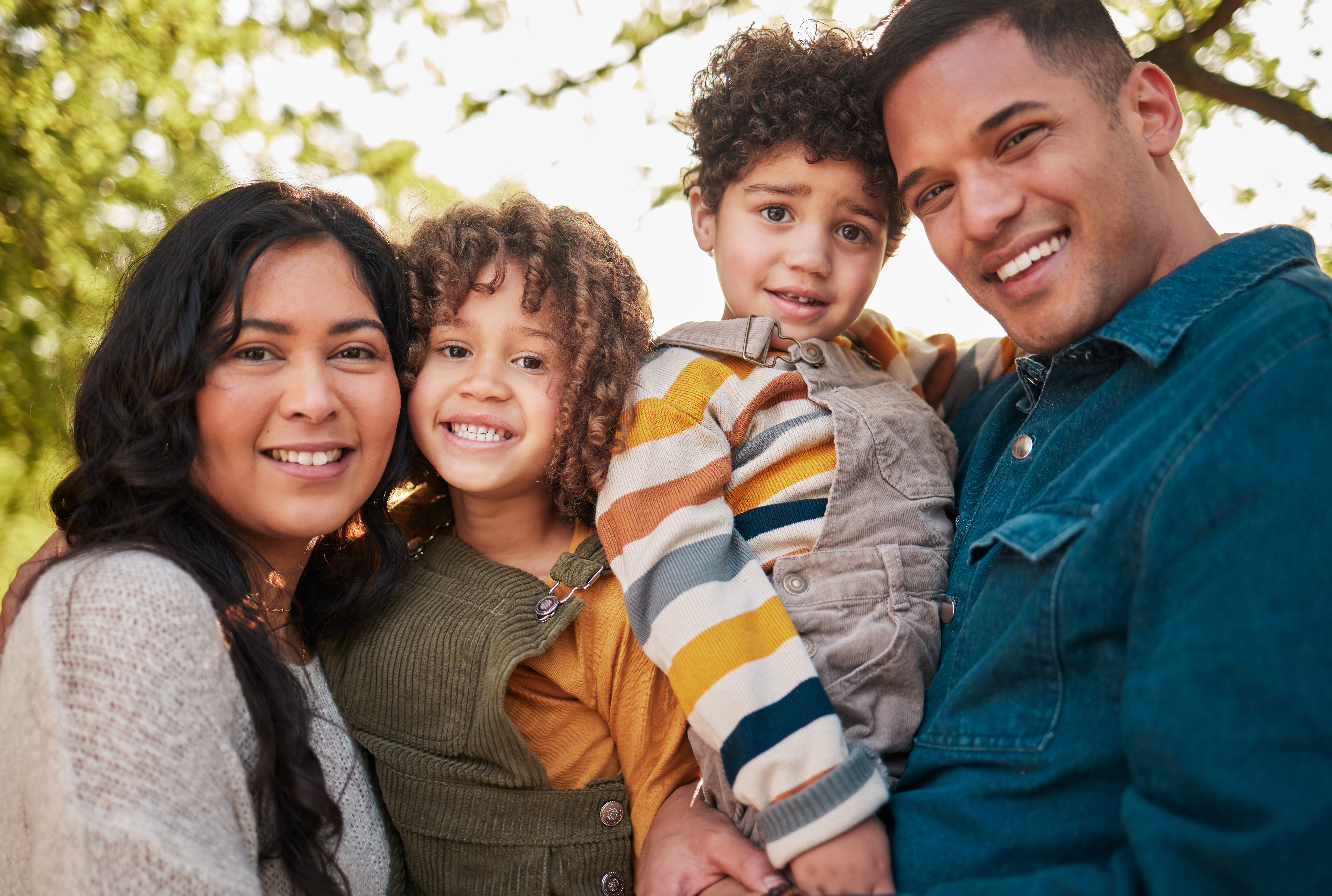 A happy parent smiling with their children during a portrait in a sunny Dundalk, MD park
