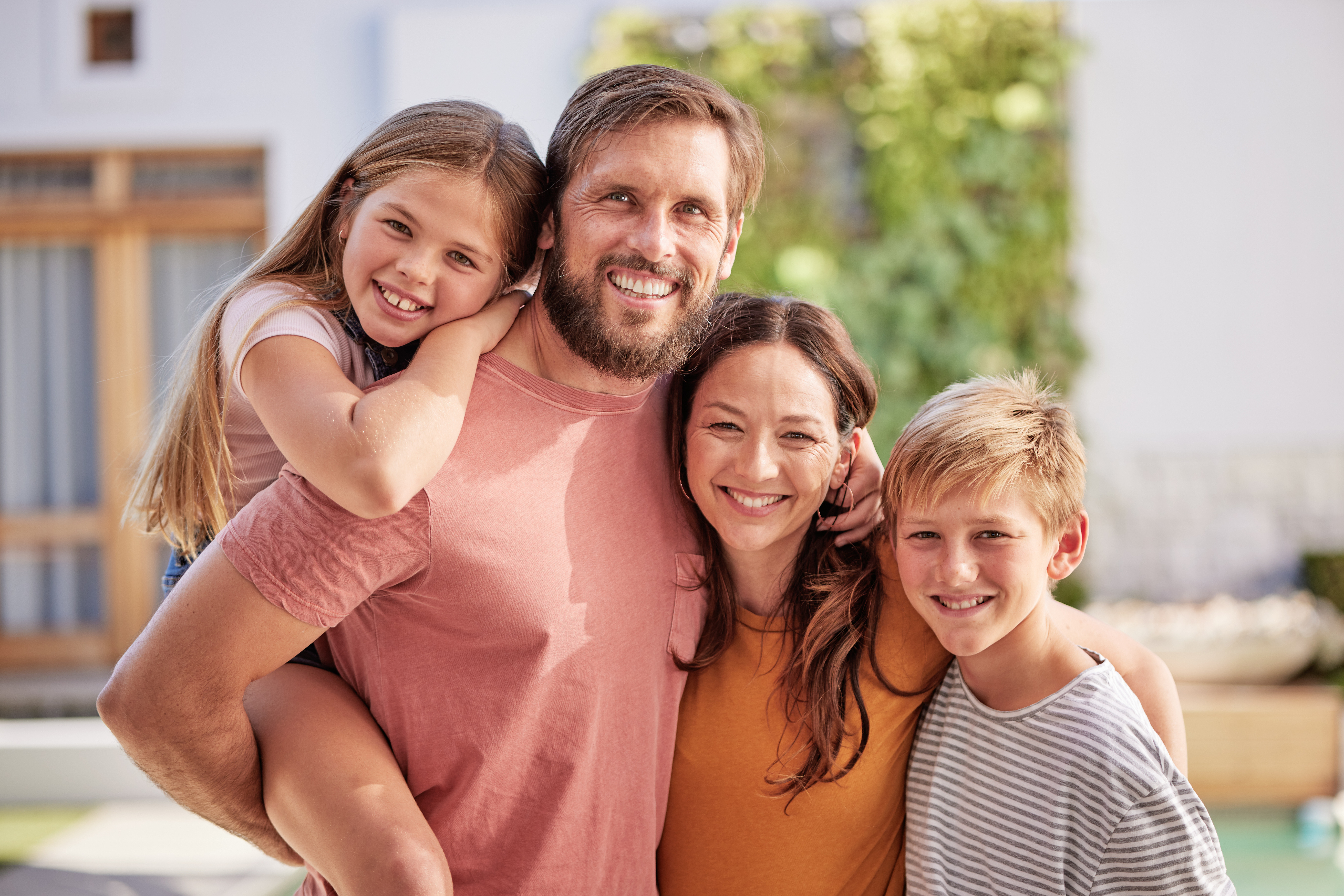 A portrait of a smiling family posing together in a sunny Newport News community park