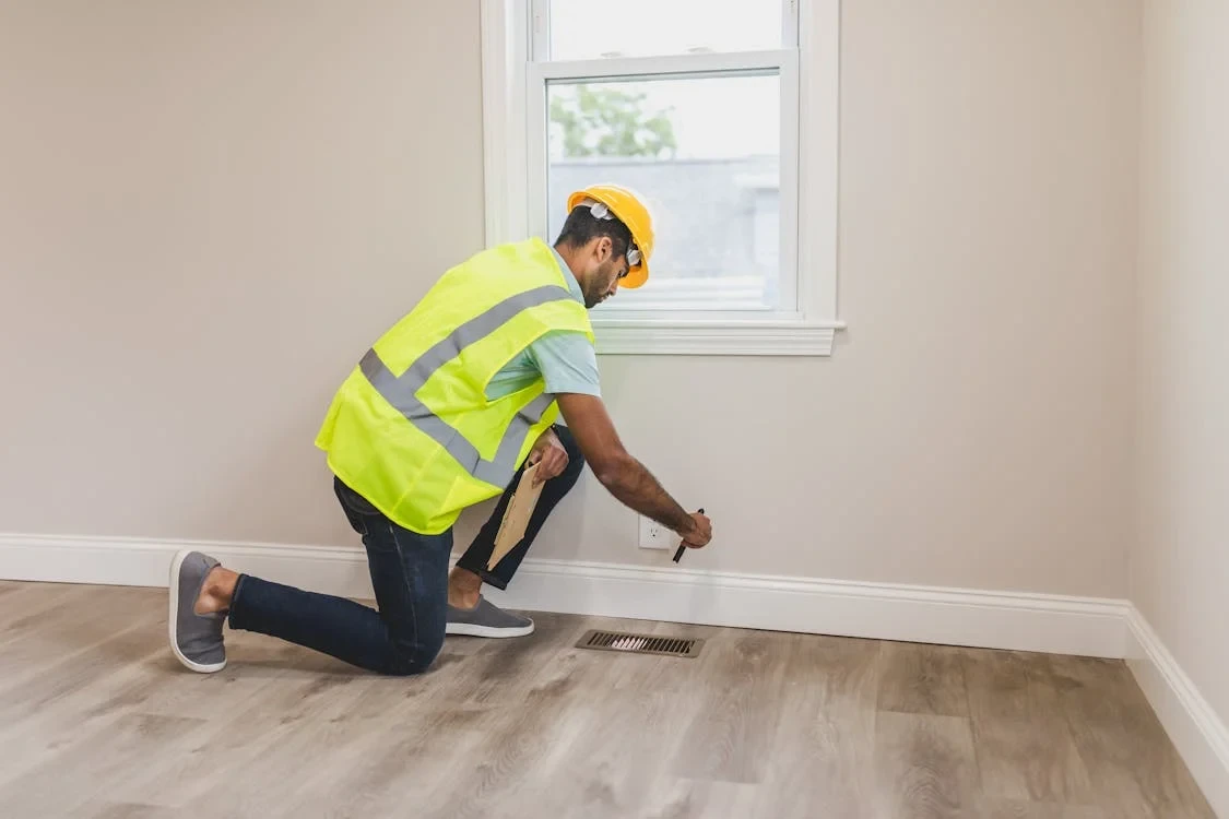 man wearing yellow green safety vest and helmet checking the floor of a house