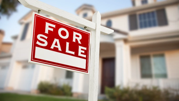 close up of for sale sign in front of home