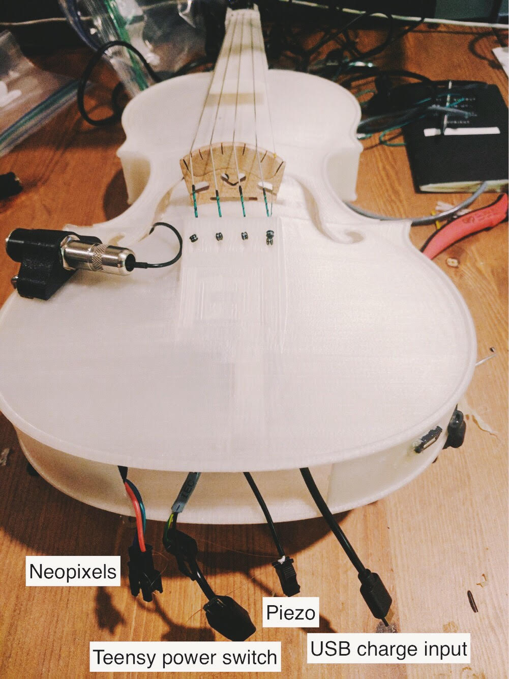 3d printed translucent violin with all the power connectors showing including the following: neopixels, teensy power switch, piezo, usb charger input