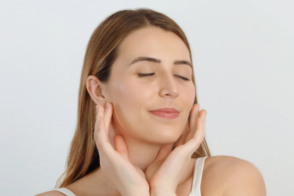 Close up of girl with eyes closed touching her face