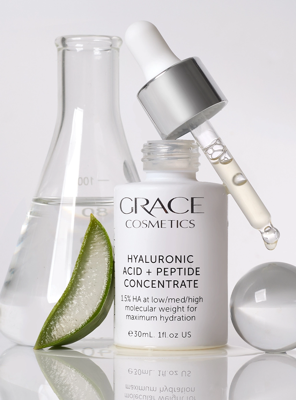 Close up of Hyaluronic Acid + Peptide Concentrate with Marine Collagen in studio setting with lab supplies and aloe slices