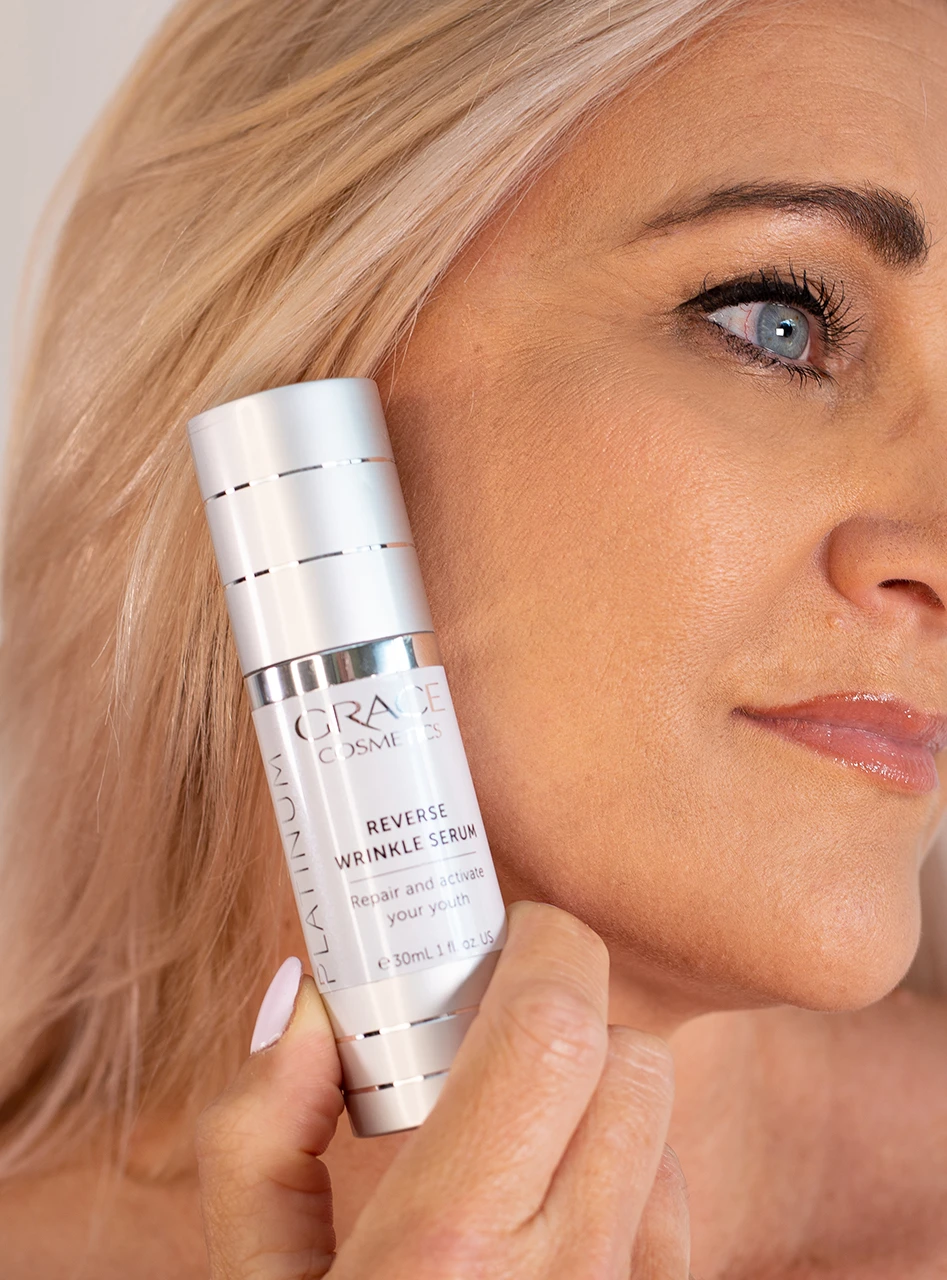 Person holding Platinum Reverse Wrinkle Serum on side of face