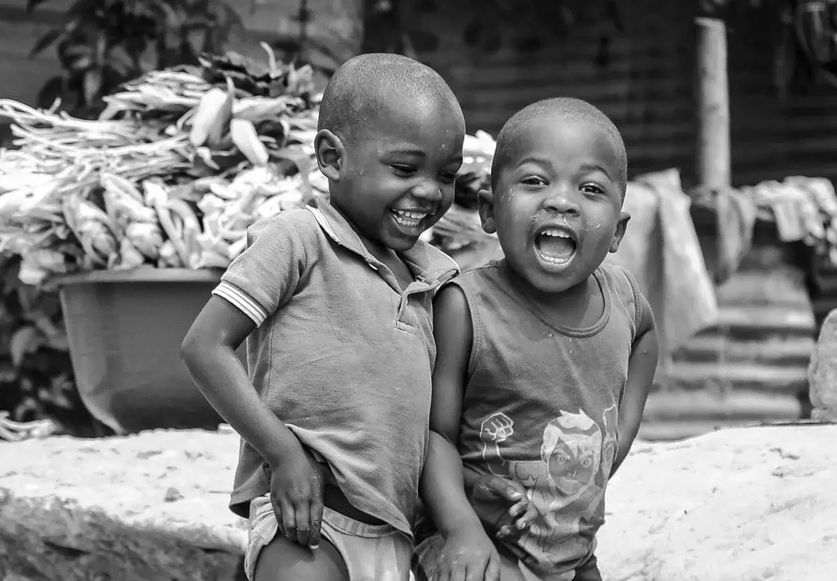 black and white photo of two african young boys holding each other and smiling