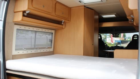 Compact bus camper with large fixed bed