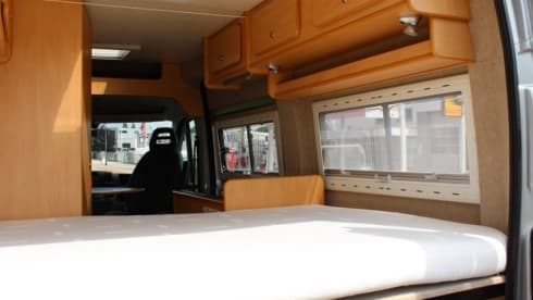 Compact bus camper with large fixed bed