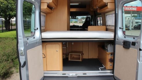 Compact bus camper with large fixed bed
