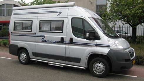 Compact bus camper with large fixed bed