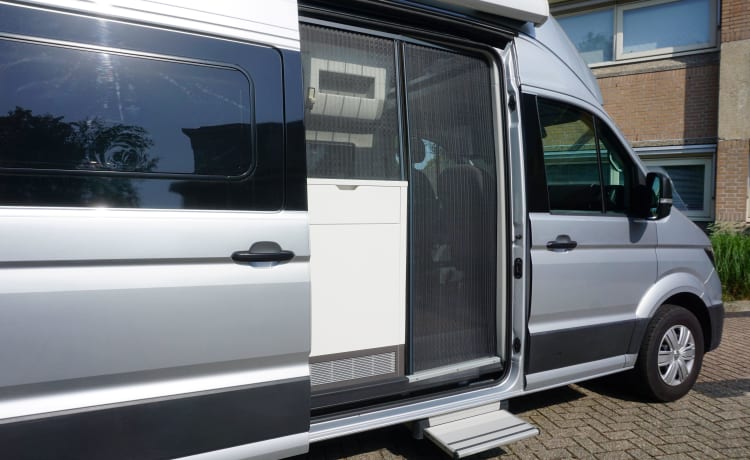 zeer stijlvolle en zeer nette VW Crafter Grand California uit 2020. Een bus camper met karakter, een ingenieuze indeling met comfort en een zeer nette grijs metallic kleur met stuurwielbediening en rondom parkeerhulp (sensoren). De VW Crafter Grand California heeft een 2.0 TDI motor met 177 PK. De Sandy B interieur Style bekleding en pilote stoelen geeft alle zitcomfort die past bij deze zeer doordacht als geriefelijk en comfortabele nette Bus camper.  De stijlvolle uitgeruste keukencenter heeft voldoende opbergmogelijkheden en is onder andere uitgerust met een 2-pits gasconform, Absorptie-koelkast, spoelbakafdekking. De bus is daarnaast voorzien van extra getinte ramen achter, elektrisch verstel- en verwarmbare buitenspiegels en een touchscreen centrale bedieningsunit.  De VW Crafter Grand California is verder onder meer uitgerust met:  Comfortline pakket van VW l Isofix l Cruise control incl. snelheidsbegrenzer l Start-stopsysteem met terugwinning l Centrale deurvergrendeling l Electrische ramen en spiegels l Trekhaak l Huishoudaccu l Cassette luifel l Standkachel  l Rondom parkeersensoren l Xenon koplampen met LED dagrijverlichting l Multifunctioneel lederen stuur l VW Multimediasysteem l Massasleutel hoofstroomschakelaar l Geïntegreerde blinderingen l Stoelen verwerkt in achterklep l    Chassis en Motor  De zuinig rijdende VW Crafter Grand California met een  2.0 TDI dieselmotor en 177 pk gecombineerd met een automatische versnellingsbak is zeer netjes en in goede staat. De camper is voorzien van nagenoeg nieuwe banden  – 3er Volkswagen Bus aus dem Jahr 2020