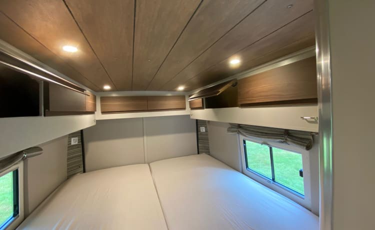 Buscamper Fiat Ducato met luxe stoelen en een groot 2 persoons bed.