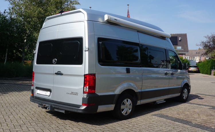 zeer stijlvolle en zeer nette VW Crafter Grand California uit 2020. Een bus camper met karakter, een ingenieuze indeling met comfort en een zeer nette grijs metallic kleur met stuurwielbediening en rondom parkeerhulp (sensoren). De VW Crafter Grand California heeft een 2.0 TDI motor met 177 PK. De Sandy B interieur Style bekleding en pilote stoelen geeft alle zitcomfort die past bij deze zeer doordacht als geriefelijk en comfortabele nette Bus camper.  De stijlvolle uitgeruste keukencenter heeft voldoende opbergmogelijkheden en is onder andere uitgerust met een 2-pits gasconform, Absorptie-koelkast, spoelbakafdekking. De bus is daarnaast voorzien van extra getinte ramen achter, elektrisch verstel- en verwarmbare buitenspiegels en een touchscreen centrale bedieningsunit.  De VW Crafter Grand California is verder onder meer uitgerust met:  Comfortline pakket van VW l Isofix l Cruise control incl. snelheidsbegrenzer l Start-stopsysteem met terugwinning l Centrale deurvergrendeling l Electrische ramen en spiegels l Trekhaak l Huishoudaccu l Cassette luifel l Standkachel  l Rondom parkeersensoren l Xenon koplampen met LED dagrijverlichting l Multifunctioneel lederen stuur l VW Multimediasysteem l Massasleutel hoofstroomschakelaar l Geïntegreerde blinderingen l Stoelen verwerkt in achterklep l    Chassis en Motor  De zuinig rijdende VW Crafter Grand California met een  2.0 TDI dieselmotor en 177 pk gecombineerd met een automatische versnellingsbak is zeer netjes en in goede staat. De camper is voorzien van nagenoeg nieuwe banden  – Autobus Volkswagen 3p à partir de 2020