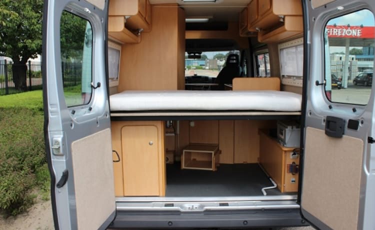 Compact bus camper with large fixed bed